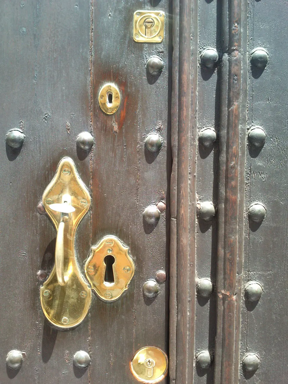 Detall d’una porta de fusta amb ferramenta i un picaporta daurat
