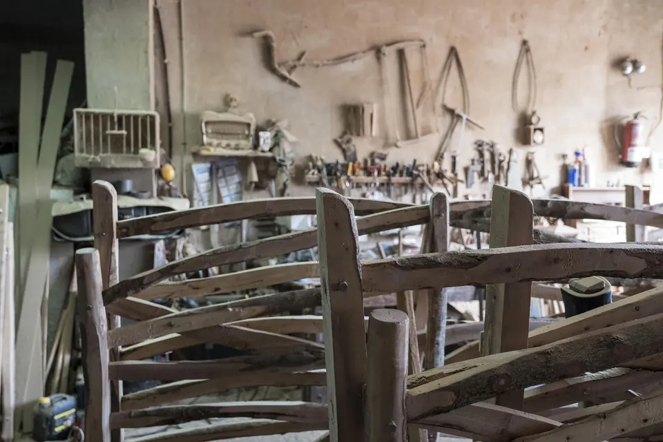 Taller de fusteria amb eines penjades i cadires de fusta