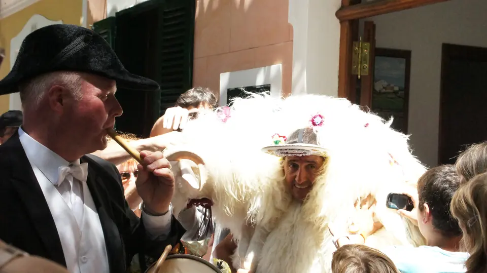 Home amb vestit tradicional i gorra de pell al costat d’un altre personatge de festes