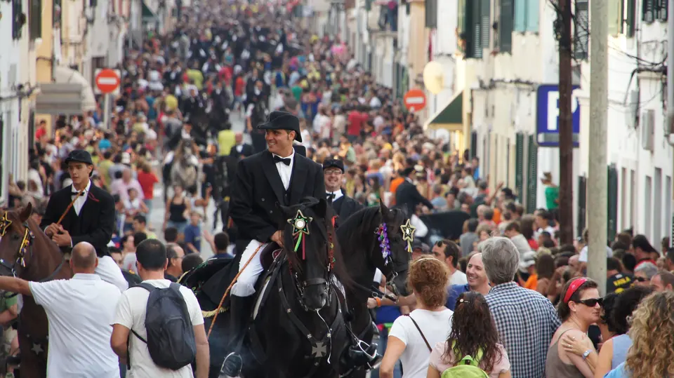 Multitud en un carrer amb genets a cavall durant unes festes