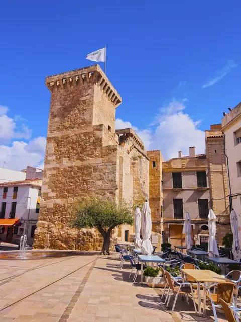 Torre de pedra i façanes en una plaça de poble
