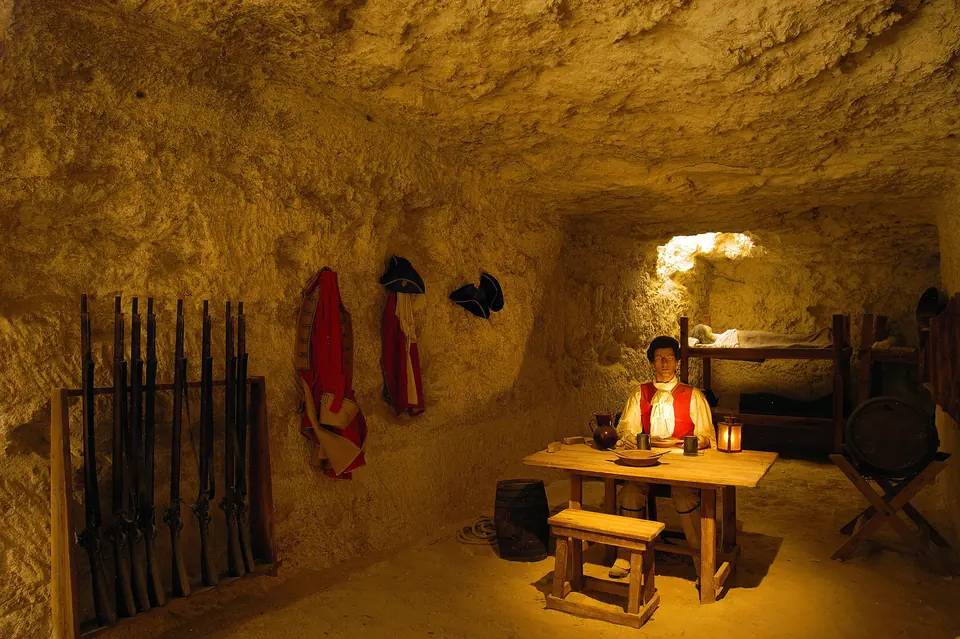 Recreació històrica en una estança excavada a la roca, amb mobiliari i armes