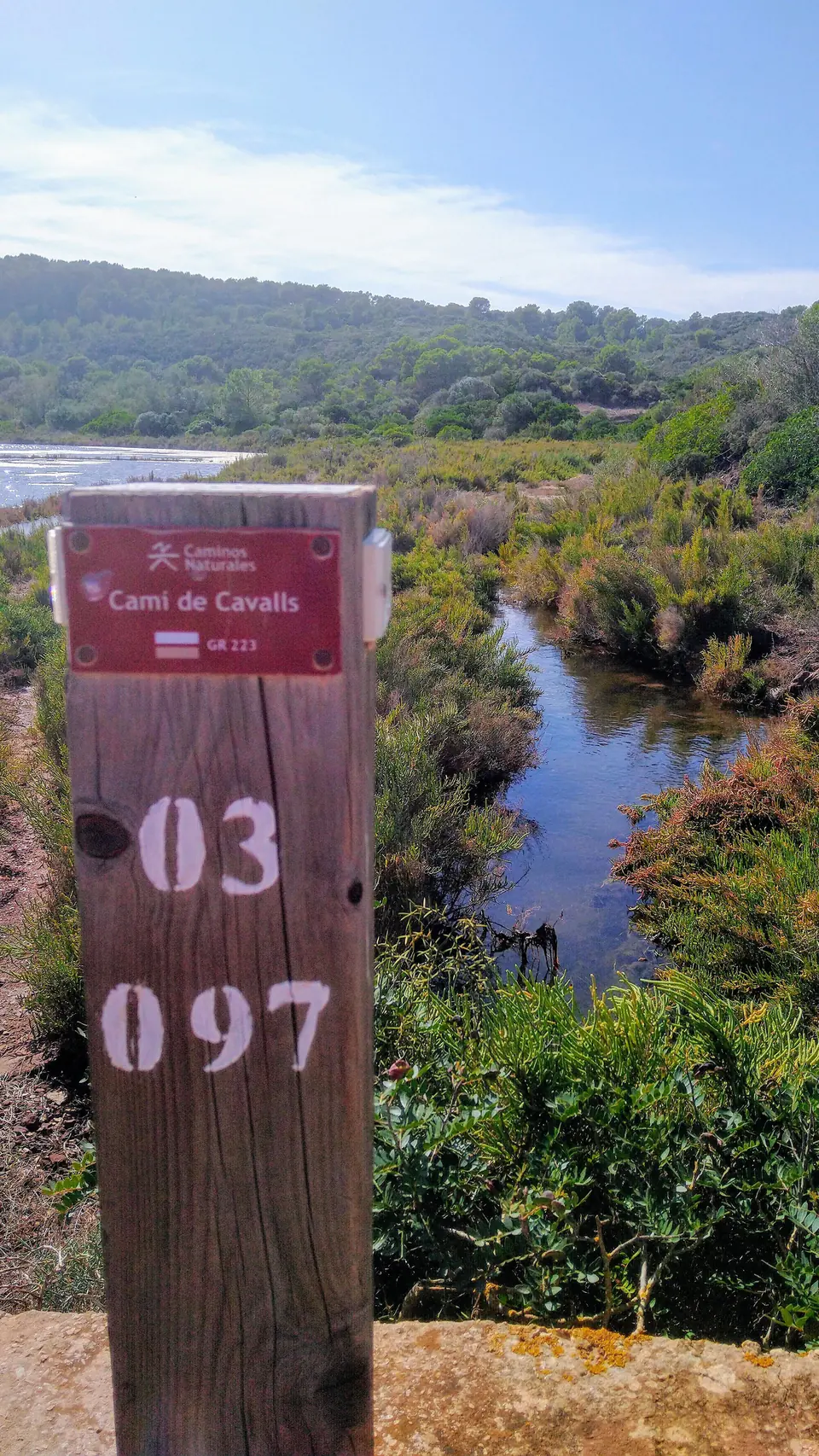 Fita del Camí de Cavalls amb la numeració de l’etapa vora un canal d’aigua