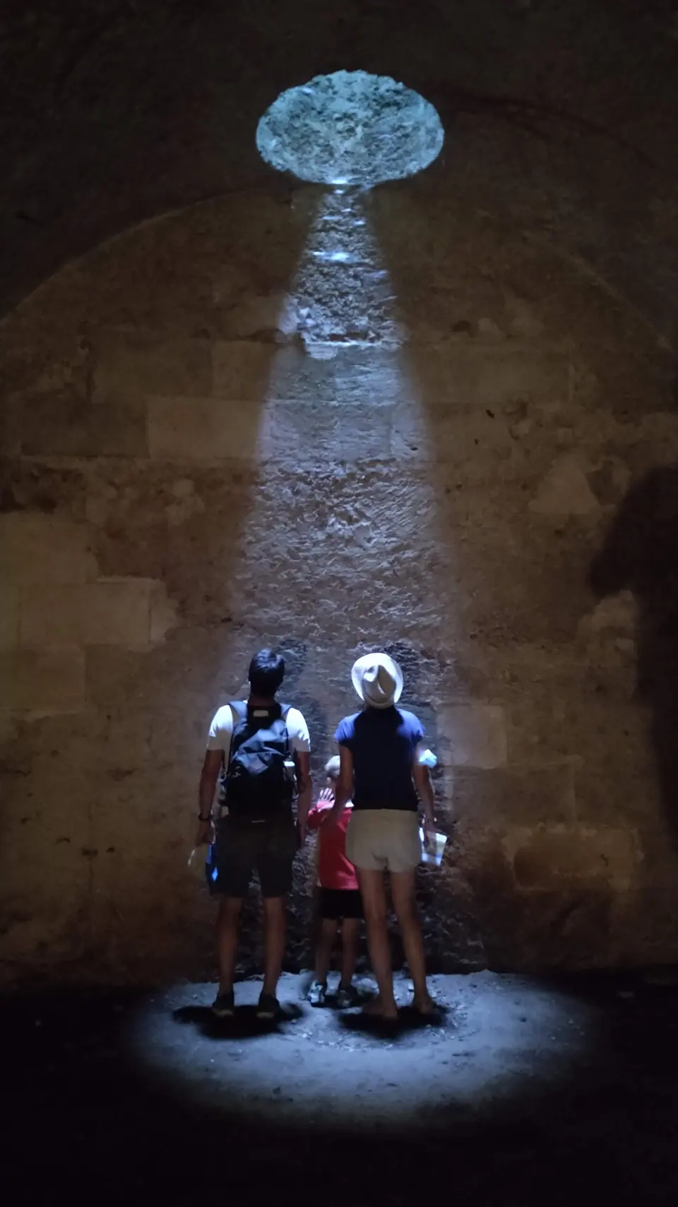 Dos visitants sota un raig de llum a l’interior d’una cambra subterrània