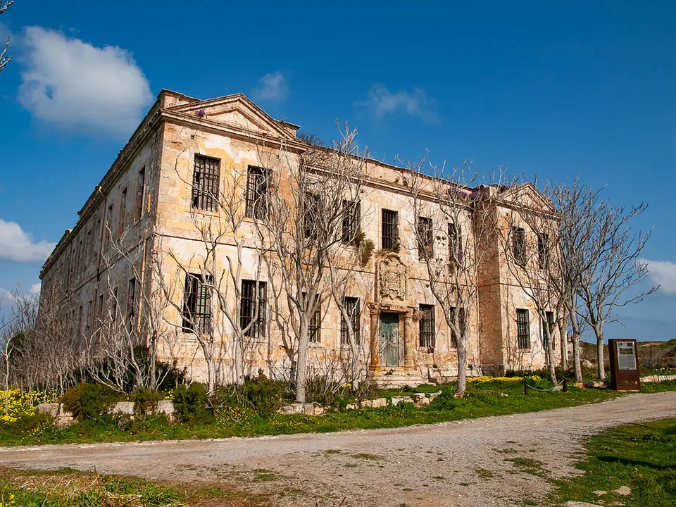 Antic edifici de pedra de diverses plantes vora un camí rural