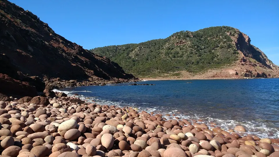 Es Macar d’Alfurinet: platja de còdols rogencs amb un cap al fons