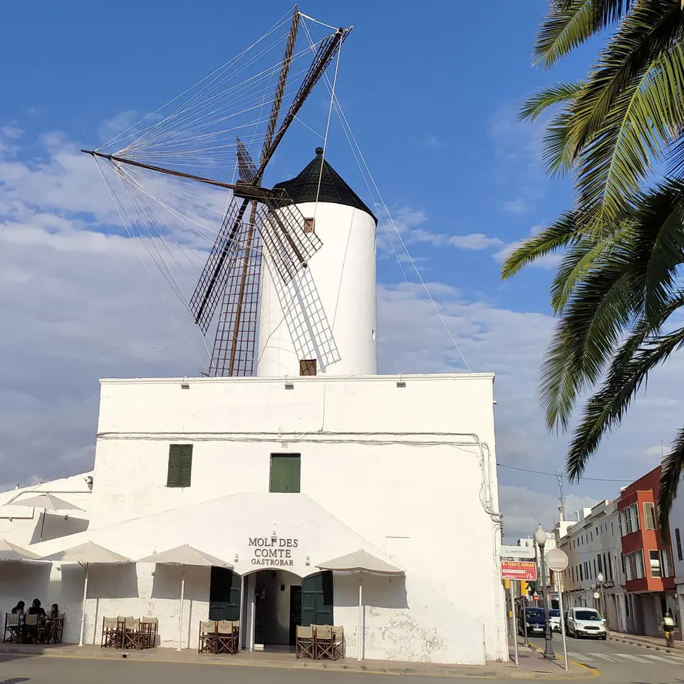 Molí de vent i casa blanca en un poble
