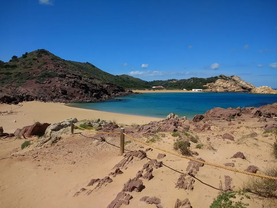 Pregondó: platja de sorra rogenca amb una passarel·la de cordes
