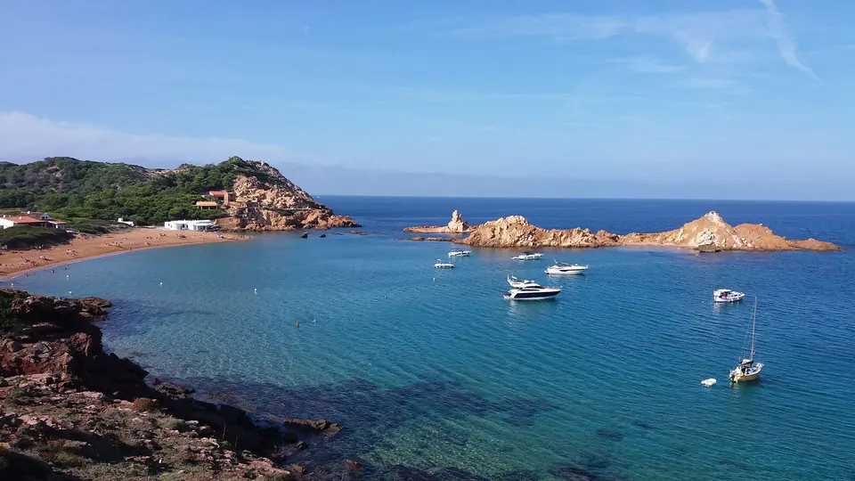 Cala Pregonda: costa rocosa amb illots i vaixells fondejats