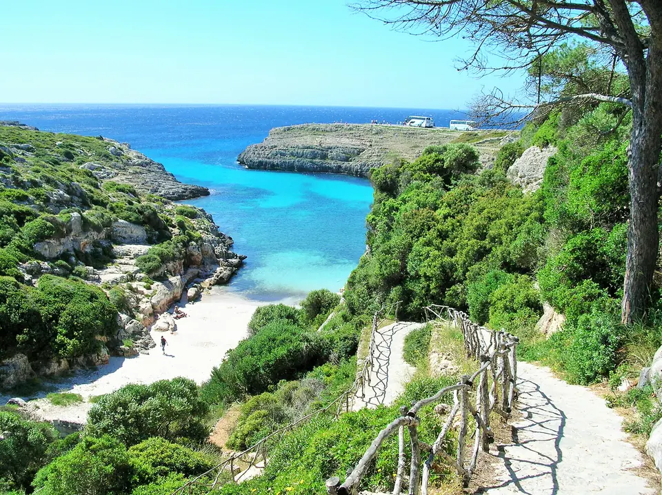 Binidalí: cala d’aigües turquesa amb un sender de fusta entre la vegetació