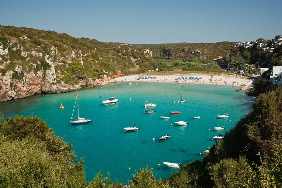 Cala en Porter: cala d’aigües turquesa amb barques entre penya-segats