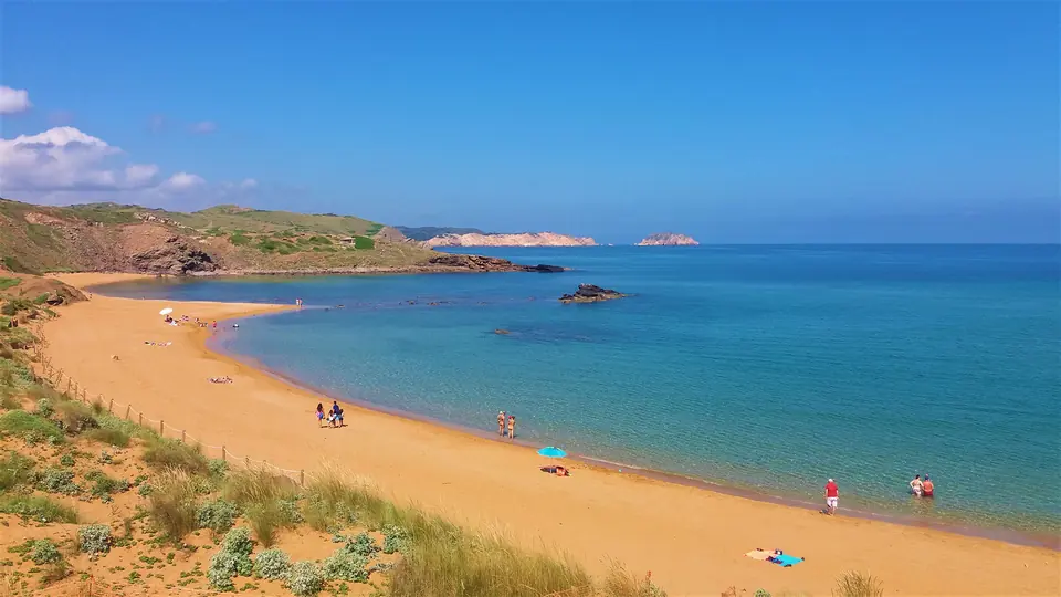 Cavalleria: platja de sorra ataronjada i aigües turquesa