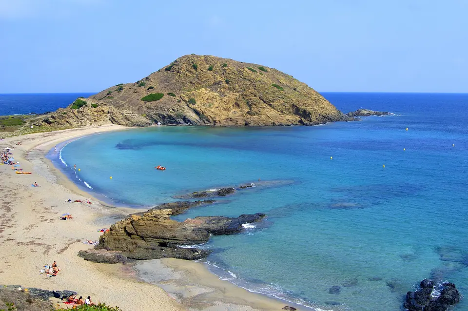 Sa Mesquida: platja de sorra amb un cap rocós i aigües blaves