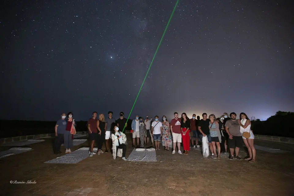 Grup de persones observant el cel nocturn amb un punter làser verd