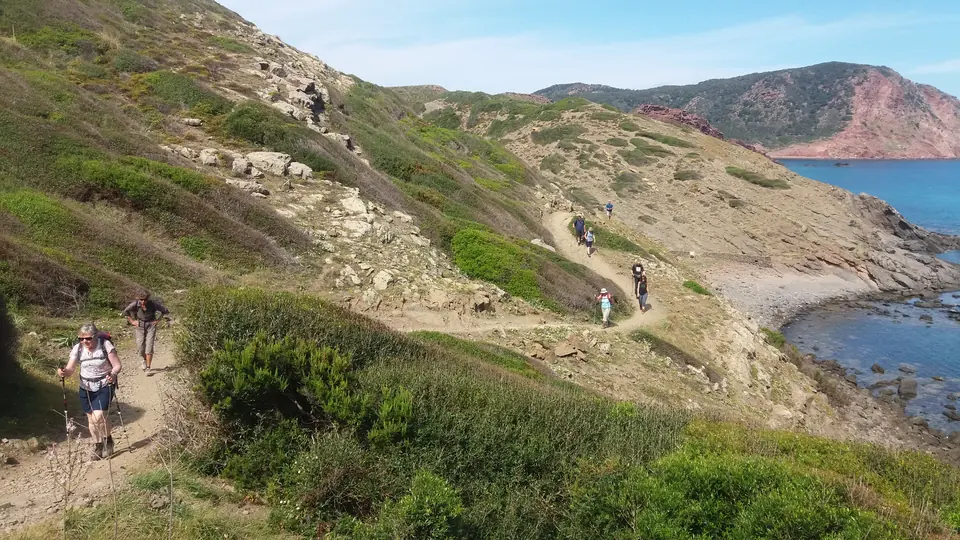 Excursionistes en un sender entre turons i costa